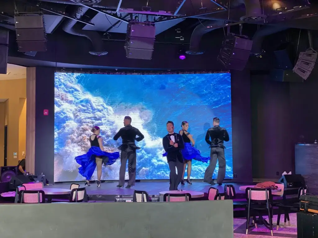 Dancers performing on stage with video wall in the background